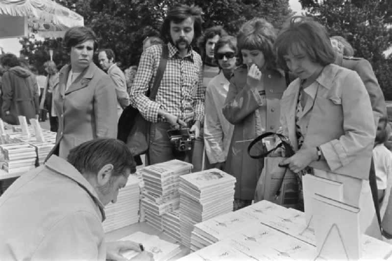 Writers' bazaar on the grounds of the IGA in the Rose Garden on the occasion of the 15th Workers' Festival in Erfurt in the federal state of Thuringia in the territory of the former GDR, German Democratic Republic. Heinz Knobloch ( author and feature writer ) signs one of his books at the book bazaar