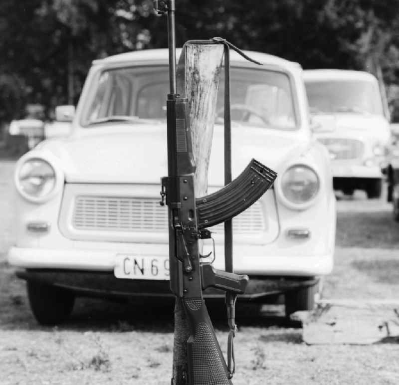 Icon image, a rifle branded AK 47 in front of a Trabant in Ferdinandshof in Mecklenburg-Western Pomerania in the field of the former GDR, German Democratic Republic