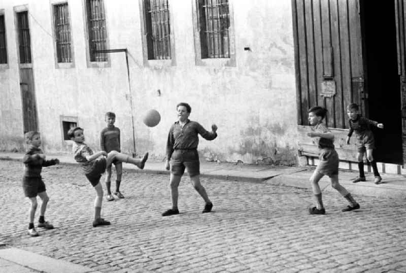 Jungen spielen Fußball auf einer Straße in Freiberg.