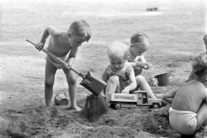 Kleine Kinder vergnügen sich beim Buddeln im Sand im Clara-Zetkin-Park in Leipzig.