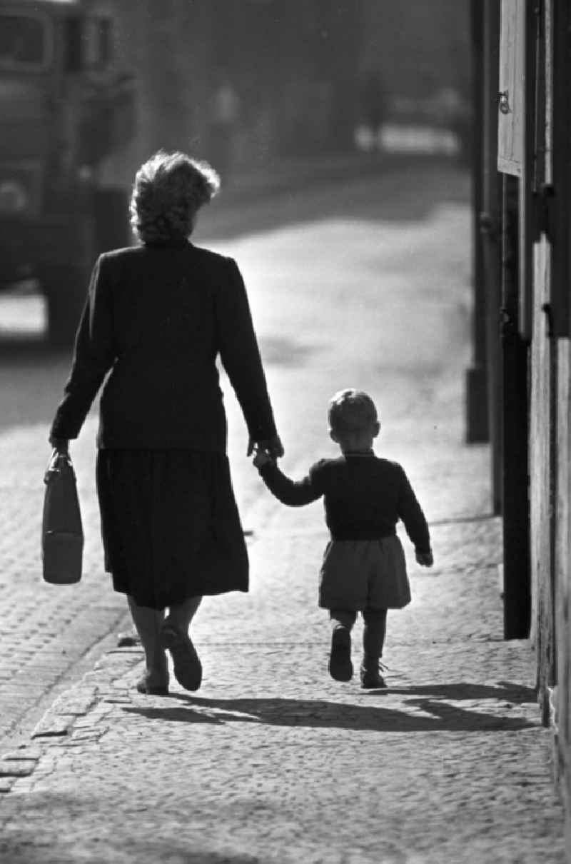 Hand in Hand läuft eine Frau mit ihrem kleinen Jungen durch eine Straße in Freyburg an der Unstrut.