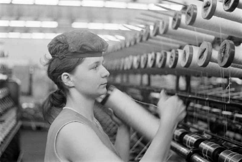 Female worker with hairnet changes a coil on a direct cabling machine for tire cord in the production plant and operating facilities of the VEB Reifenkombinat Fuerstenwalde, later Pneumant Reifen Gmbh and Goodyear, in Fuerstenwalde/Spree in the state Brandenburg on the territory of the former GDR, German Democratic Republic