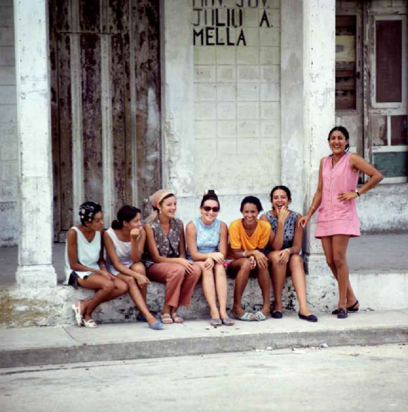 Junge Frauen sitzen auf der Stufe eines Hauses in Gibara in Kuba.