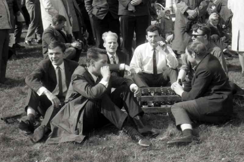 Men sitting together on the floor, next to a crate of beer, drinking beer and smoking during an event in Gotha in the German state of Thuringia in Gotha in the state Thuringia on the territory of the former GDR, German Democratic Republic