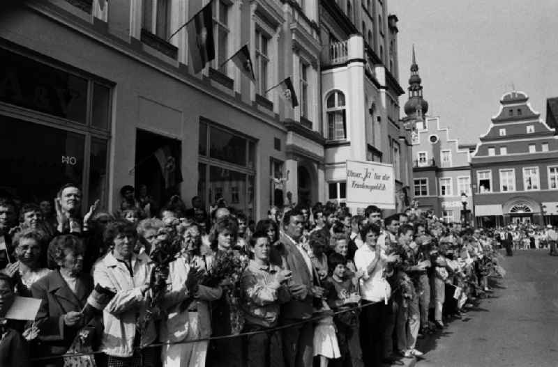 Besuch von Erich Honecker anlässlich der Domweihe. Passanten / Schaulustige auf Marktplatz warten auf Honecker, stehen hinter Absperrung und geben Applaus. DDR-Flaggen hängen an Gebäuden. Transparent / Plakat über der Menge 'Unser 'Ja' für die Friedenspolitik'.