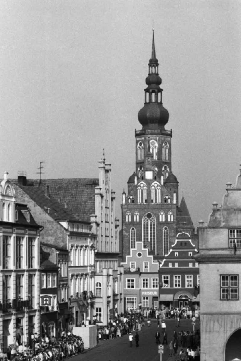 Besuch von Erich Honecker anlässlich der Domweihe. Passanten / Schaulustige auf Marktplatz am Rathaus. DDR-Flaggen hängen an Gebäuden. Im Hintergrund Dom St. Nikolai.