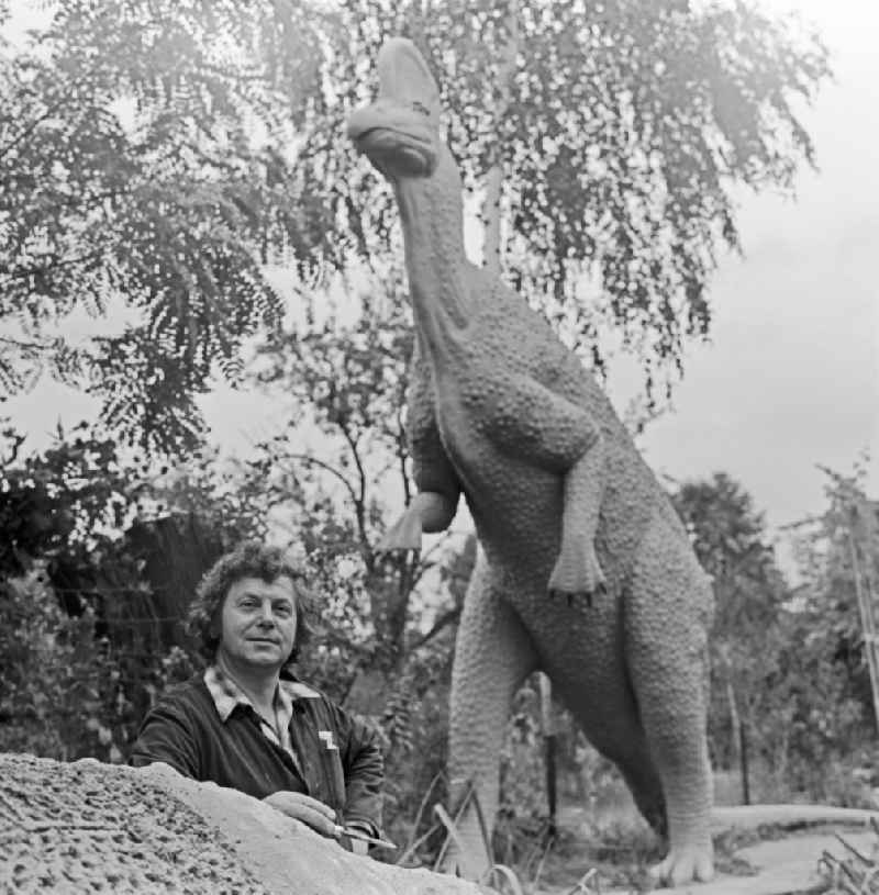 Paths along trees and bushes in the 'Saurier Park Kleinwelka' park with the builder of the dinosaur garden Franz Gruss in front of a large dinosaur sculpture in Gross Welka, Saxony in the area of ??the former GDR, German Democratic Republic