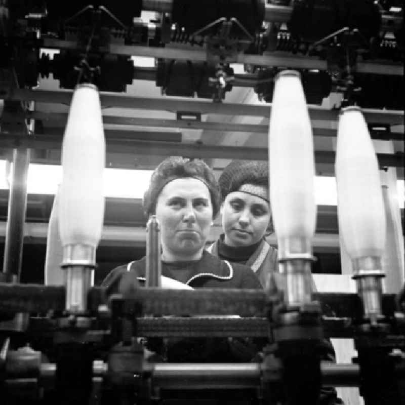 Zwei Arbeiterinnen hinter Maschine, betrachten aufgerolltes Garn auf Spule im VEB Chemiefaserwerk 'Herbert Warnke' Guben.