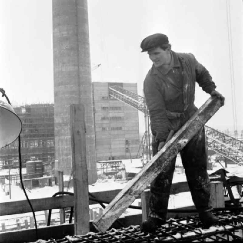 Arbeiter hebt Balken auf Baustelle am VEB Chemiefaserwerk 'Herbert Warnke' Guben.