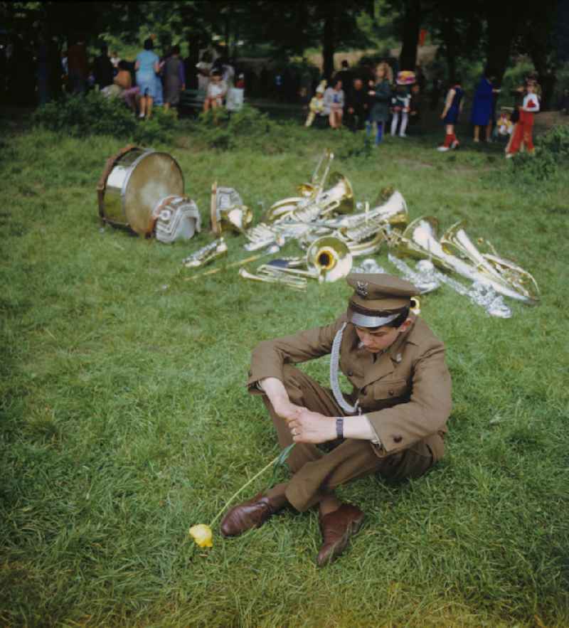 Zum Festprogramm des Frühlingsfestes in Gubin sitzt ein Mitglied der Musikkappelle mit einer Tulpe in der Hand vor den im Gras liegenden Blechblasinstrumenten.
