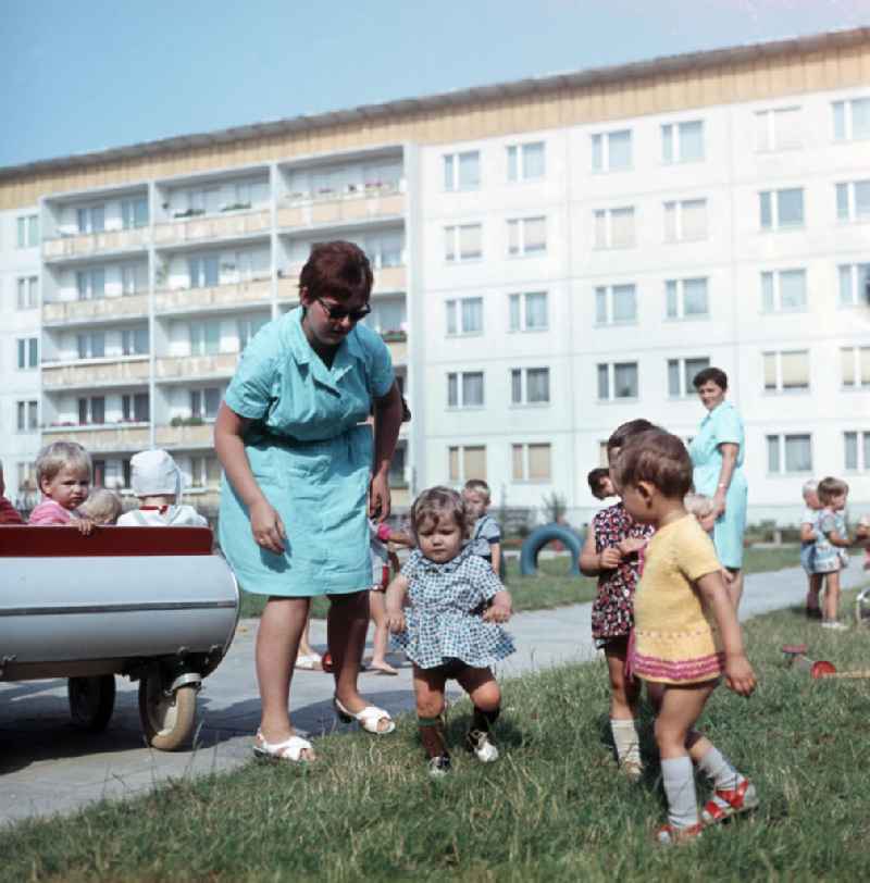 Eine Erzieherinn kümmert sich in einem Kindergarten in Halle-Neustadt um ein kleines Kind. Am Standort der Chemieindustrie der DDR wurde in den 1960er und 197