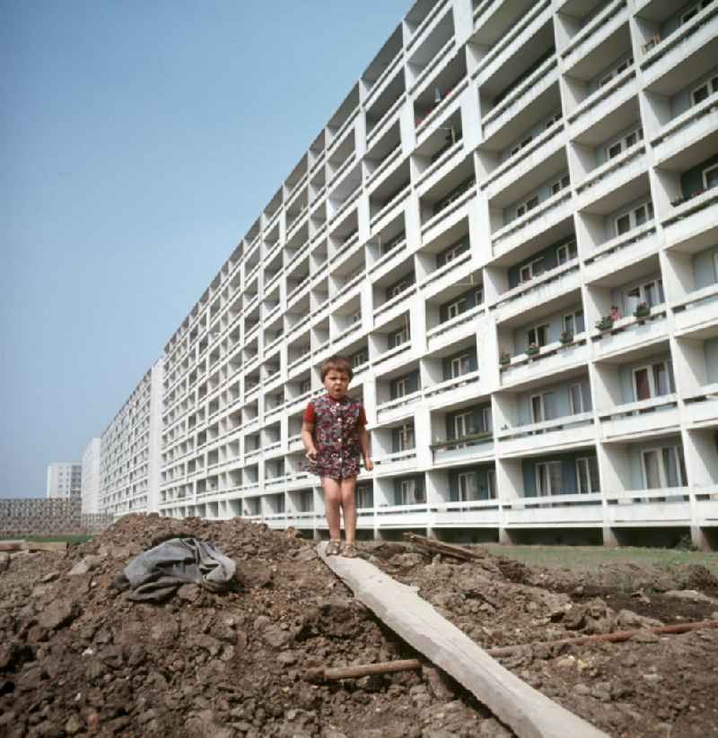 Ein Mädchen balanciert auf einem Brett in einem Neubaugebiet in Halle-Neustadt. Die Umgebung erinnert noch an eine Baustelle, aber die ersten Mieter sind schon in die fertigen Wohnhäuser eingezogen. Am Standort der Chemieindustrie der DDR wurde in den 1960er und 197
