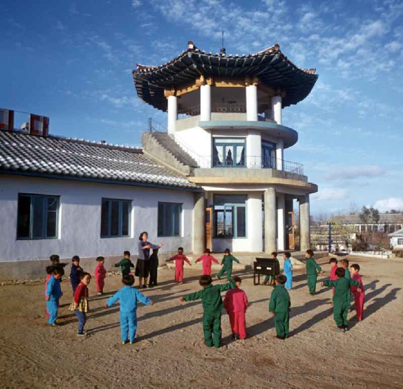 Kinder in 'Einheitsanzügen' tanzen zur Klaviermusik ihrer Erzieherin in einem LPG-Kindergarten nahe der Hafenstadt Hamhung in der Koreanischen Demokratischen Volksrepublik KDVR - Nordkorea / Democratic People's Republic of Korea DPRK - North Korea.