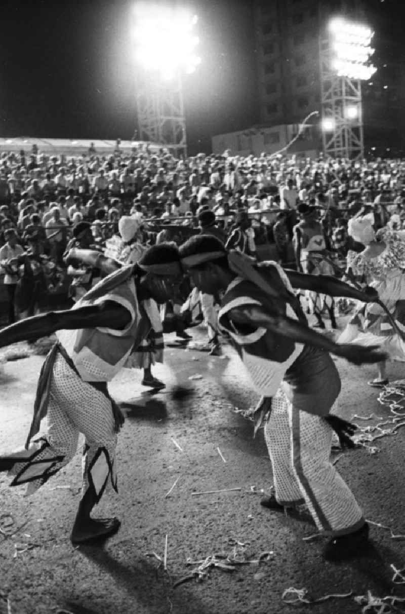 Karneval während der XI. Weltfestspiele der Jugend und Studenten vom 28.07. - 05.08.1978. Im Fokus zwei Tänzer, die einander umkreisen. Im Hintergrund: vollbesetzte Zuschauertribünen. Karneval hat auf Kuba eine lange Tradition, besonders in Santiago de Cuba. Er verschmilzt karibische, brasilianische und afrikanische Einflüsse. Die Weltfestspiele standen unter dem Motto: 'Für antiimperialistische Solidarität, Frieden und Freundschaft'. 18.500 Jugendliche aus 145 Ländern nahmen teil, darunter 20