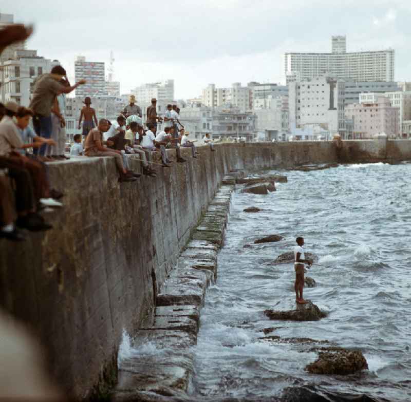 Angler sitzen auf der Mauer an der acht Kilometer langen Uferpromenade, dem sogenannten Malecón, in der kubanischen Hauptstadt Havanna.