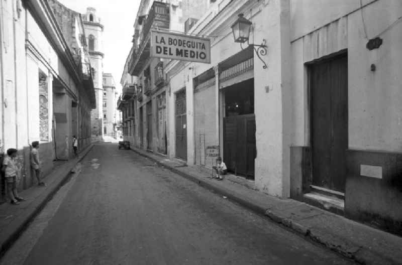 Kinder stehen neben Hauseingängen in einer Straße in Havanna, in der sich die mit dem Namen Hemmingway verbundene Bar 'La Bodeguita del Medio' befindet.
