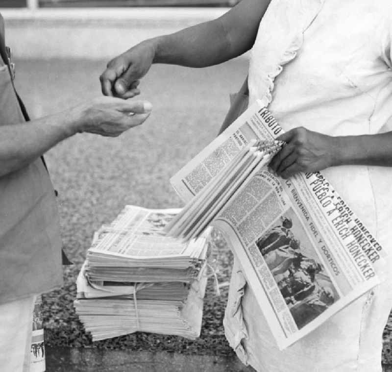Ein Passant kauft bei einer Zeitungsverkäuferin auf einer Straße in Havanna die aktuelle Ausgabe der 'Granma', der offiziellen Zeitung der Kommunistischen Partei Kubas (PCC). Die Zeitung zeigt ein Foto von der Ankunft des Staats- und Parteivorsitzenden der DDR, Erich Honecker, der vom 2