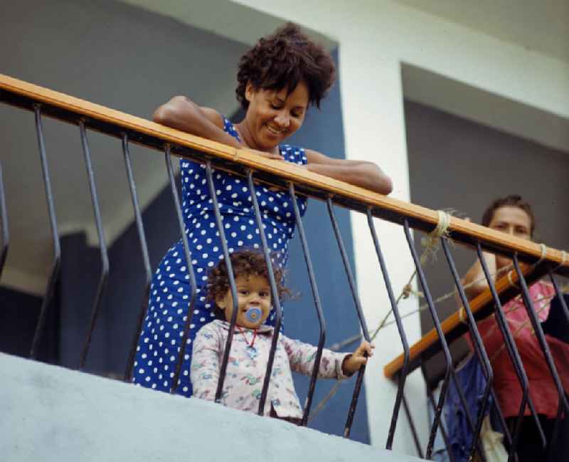 Eine Frau mit ihrem kleinen Kind schauen lachend von ihrem Balkon eines neu errichteten Wohnhauses in Plattenbauweise in Havanna Alamar. Die kubanische Neubausiedlung Alamar war einst als Symbol sozialistischen Lebens geplant worden und ist seit Mitte der 6