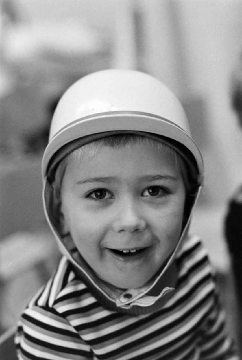 Child wearing a motorcycle helmet in the children's combination / in the kindergarten 'Puenktchen' in Hennigsdorf on the territory of the former GDR, German Democratic Republic