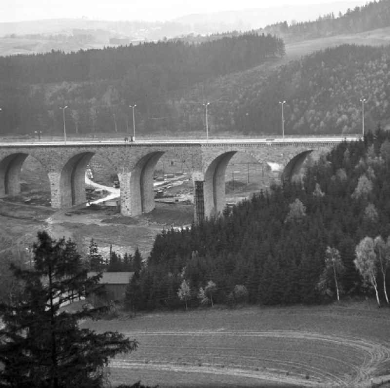 Blick auf den wiederaufgebauten Teil der Autobahnbrücke über die Saale zwischen Hirschberg (Thüringen) und Rudolphstein (Bayern). Die Brücke war am Ende des Zweiten Weltkrieges stark beschädigt, ein Bogen im April 1965 gesprengt worden. Die Instandsetzung erfolgte nach einem Vertrag zwischen der DDR und der BRD, die die Finanzierung des Baus übernahm. Im Hinterland der DDR wurden die Abfertigungsgebäude für die Grenzübergangsstelle (GÜST) Hirschberg errichtet, der Autobahn-Grenzübergang im Dezember 1966 eröffnet. Nach der Wiedervereingung erfolgte der Rückbau der Anlagen und die Erweiterung der Brücke durch den dreispurigen Ausbau der A9. Sie heißt heute auch 'Brücke der Deutschen Einheit'.