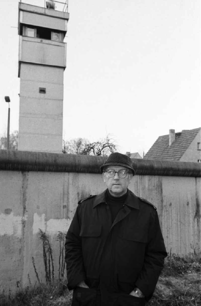 Anwohner / Mann / Rentner mit Brille und Hut steht vor Grenze / Mauer, dahinter eine Grenzturm / Wachturm der Grenzgegemeinde Stolpe.