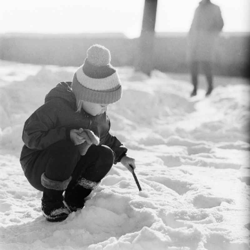 Small child with bobble hat playing in the snow in Jena in Thuringia in the area of the former GDR, German Democratic Republic