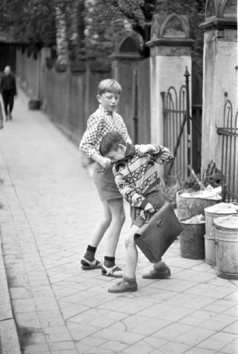 Auf dem Nachhauseweg von der Schule messen zwei Jungs bei einer kleinen Balgerei auf dem Fußweg ihre Kräfte.