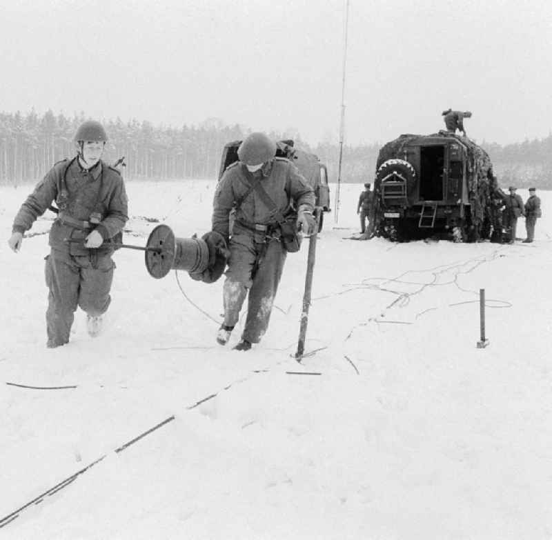 Soldiers of the 2nd news regiment of the NVA with roll out from news cable during a manoeuvre in winter in Wernsdorf in Koenigs Wusterhausen in the federal state Brandenburg in the area of the former GDR, German democratic republic