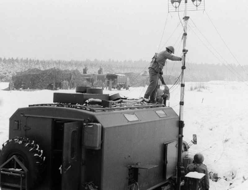 Soldiers of the 2nd news regiment of the NVA with put up to a radio aerial on a mobile vehicle during a manoeuvre in winter in Wernsdorf in Koenigs Wusterhausen in the federal state Brandenburg in the area of the former GDR, German democratic republic