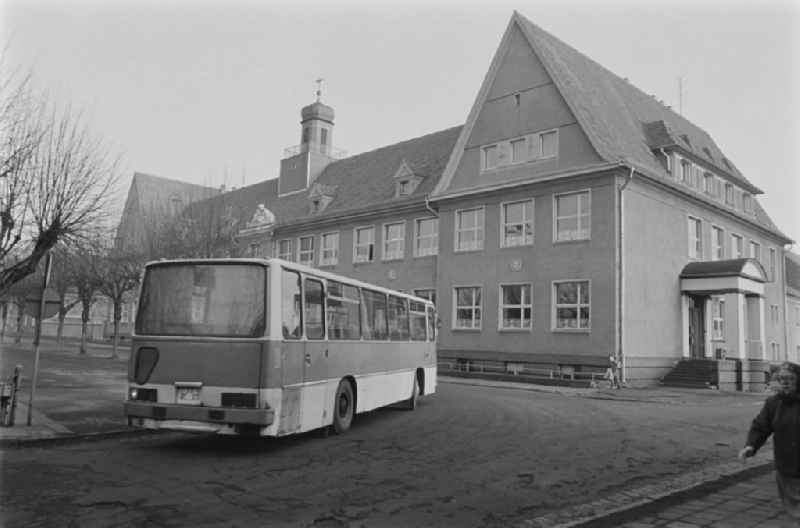 School building with tower - Secondary School OS Dr. Richard Sorge at Laubuscher Markt in the Upper Lusatian workers settlement Gartenstadt Erika in Laubusch in the state of Saxony on the territory of the former GDR, German Democratic Republic. A model Ikarus 255.72 school bus pulls up in front of the school