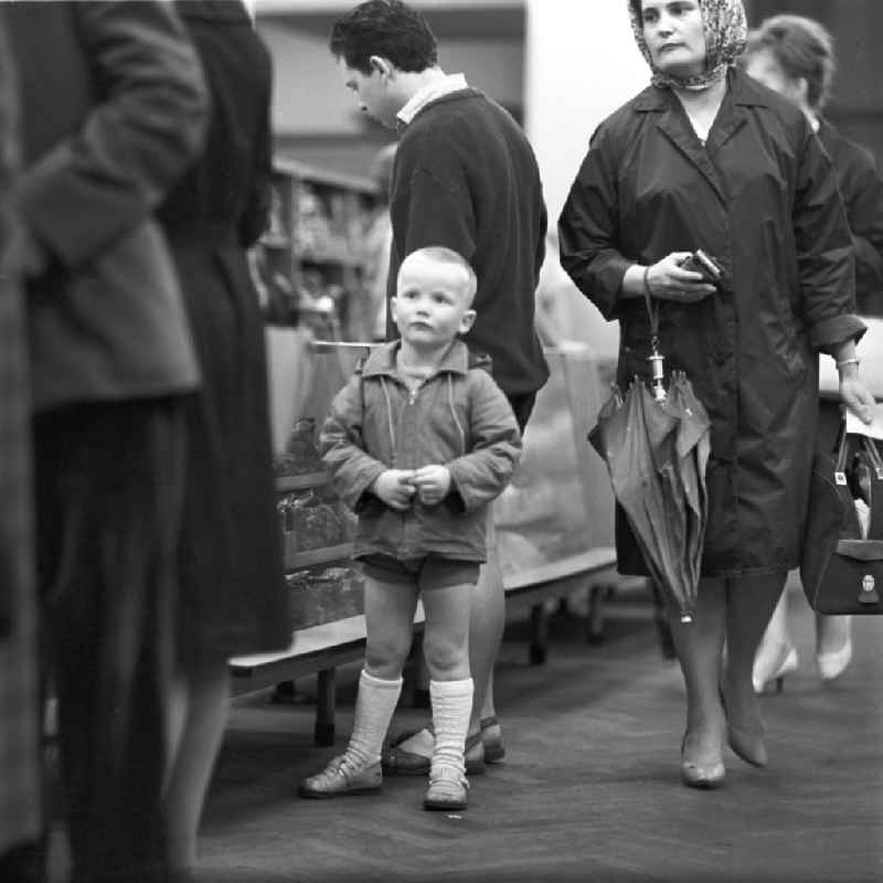 Ein kleiner Junge steht in einem Warenhaus in Leipzig und schaut neugierig dem geschäftigen Treiben zu.