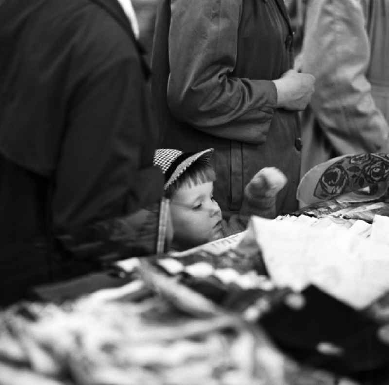Inmitten der Kunden schaut ein kleiner Junge in einem Kaufhaus in Leipzig neugierig auf die Ladentheke.