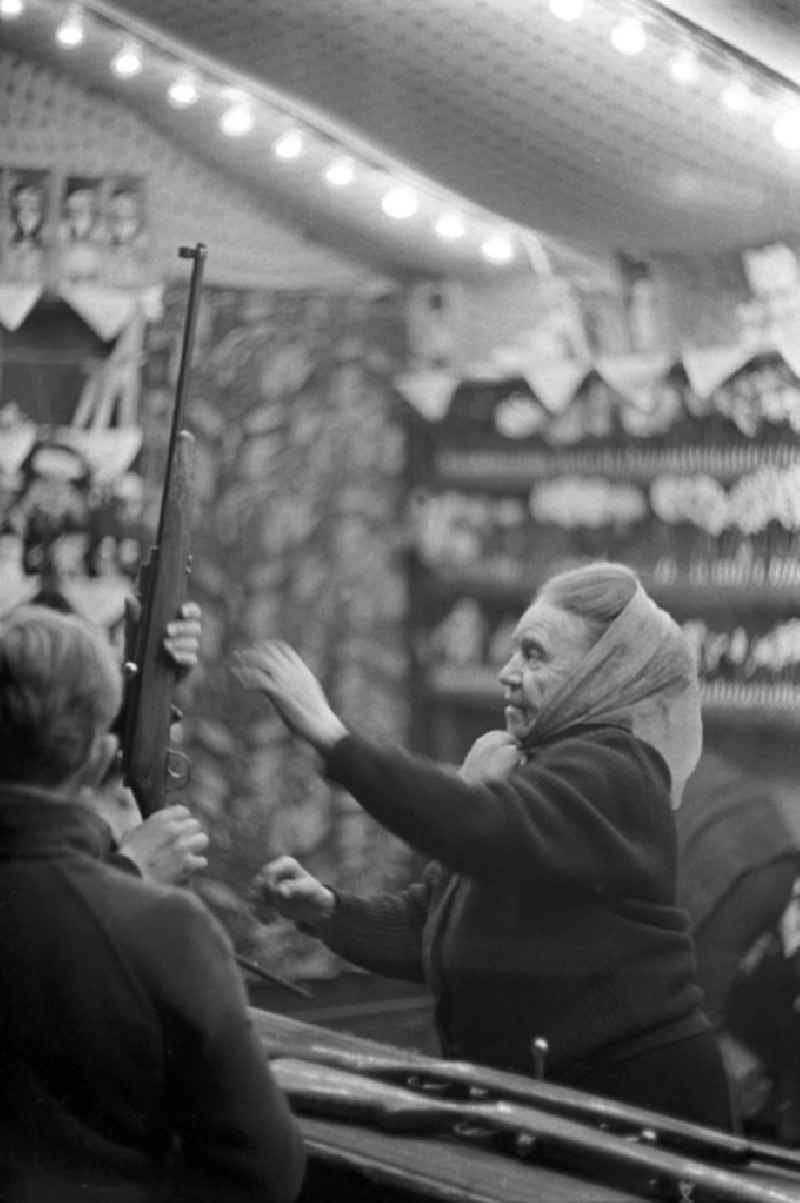 Eine Schaustellerin des Schießstandes auf dem Leipziger Weihnachtsmarkt hilft den Kunden beim Laden des Gewehres.
