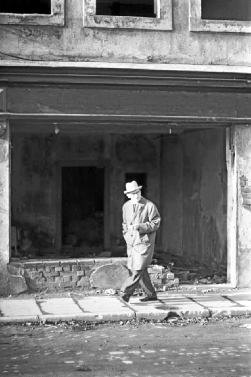 Ein Mann mit Zigarette geht während eines Spaziergangs an einem verfallenen Wohnhaus in Leipzig vorbei.