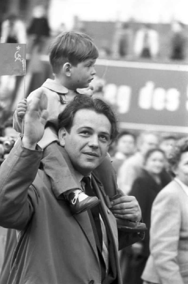 Auf der Demonstration zum 1. Mai 1958 in Leipzig sitzt ein Junge auf den Schultern seines Vaters und hält eine Sowjet-Fahne in der Hand.