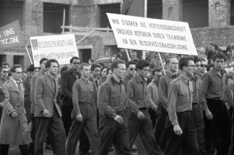 Teilnehmer an der Demonstration zum 1. Mai 1958 in Leipzig tragen Transparente mit der Aufschrift 'Wir stärken die Verteidigungskraft unserer Republik durch Teilnahme an der Reservistenausbildung' und 'FDJ - Wir schützen unser Land mit der Waffe in der Hand!'