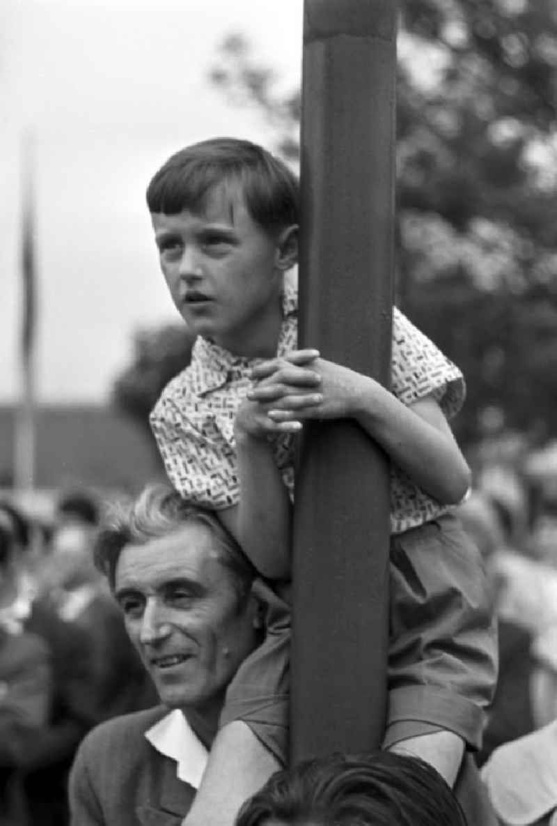 Auf den Schultern seines Vaters sitzend, schaut ein Junge zum Pressefest der Leipziger Volkszeitung gespannt einer Artistenvorführung in Leipzig zu.