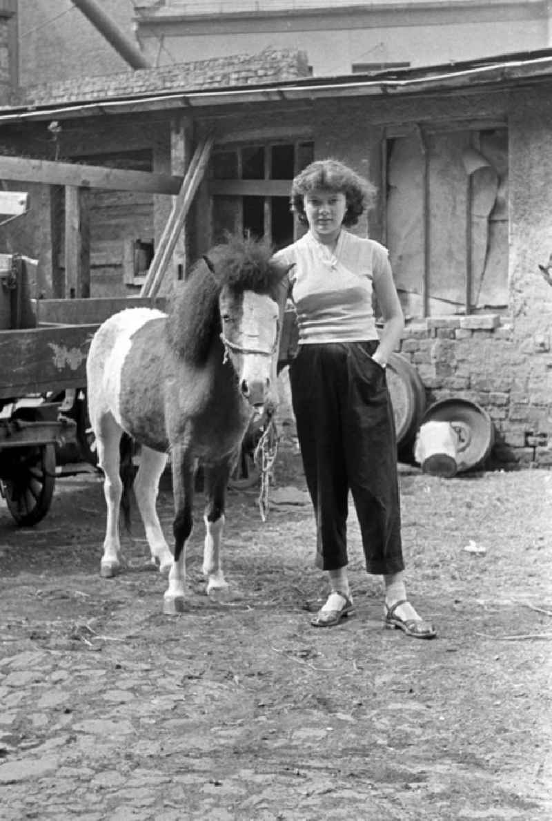 Eine junge Frau steht mit ihrem Pony auf einem verfallenen Hof in Leipzig.