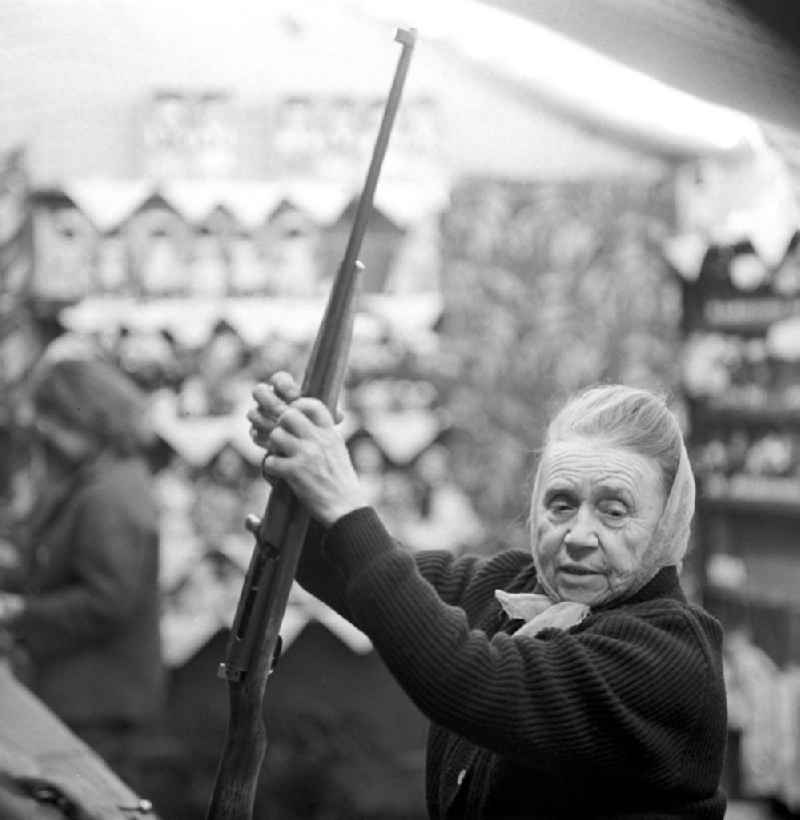 Eine Schaustellerin des Schießstandes auf dem Leipziger Weihnachtsmarkt hilft den Kunden beim Laden des Gewehres.
