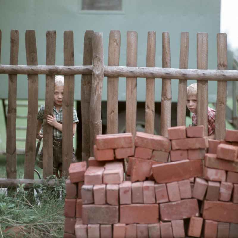 Kinder beobachten durch einen Zaun den Bau einer Volksschwimmhalle in Leipzig. Volksschwimmhallen wurden in den 1960er und 197