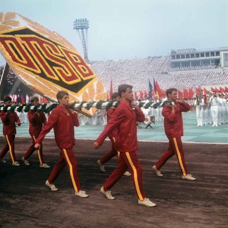 Zur Generalprobe der Sportschau zum V. Turn- und Sportfest der DDR vom 24. bis 27.7.1969 in Leipzig tragen die Teilnehmer das Symbol des Deutschen Turn- und Sportbundes (DTSB) auf ihren Schultern in das Leipziger Zentralstadion.