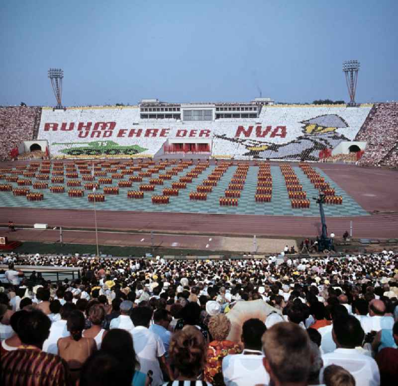 Für die Sportschau zum V. Turn- und Sportfest der DDR vom 24. bis 27.7.1969 in Leipzig gestalten die Teilnehmer im Leipziger Zentralstadion eine Veranstaltung mit Tribünenbildern und Aktionen. Die Losung lautet: 'Ruhm und Ehre der NVA'.