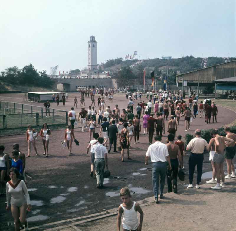 Zuschauer und Teilnehmer des V. Turn- und Sportfestes der DDR vom 24. bis 27.7.1969 in Leipzig strömen über die Festwiese in das Leipziger Zentralstadion. Im Hintergrund der Glockenturm.