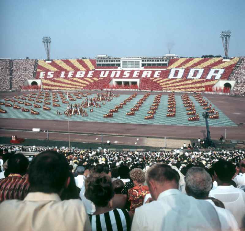 Für die Sportschau zum V. Turn- und Sportfest der DDR vom 24. bis 27.7.1969 in Leipzig gestalten die Teilnehmer im Leipziger Zentralstadion eine Veranstaltung mit Tribünenbildern und Aktionen. Die Losung lautet: 'Es lebe unsere DDR'.