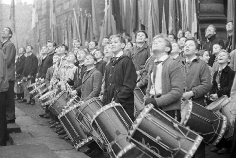 Eine Fanfarengruppe / Jungen von einem Pionier-Orchester mit einer Trommel / Trommeln betrachten  begeistert ein Spektakel anlässlich des Staatsfeiertages Tag der Republik. Der Tag der Republik war der Nationalfeiertag der DDR. Bestmögliche Qualität nach Vorlage!
