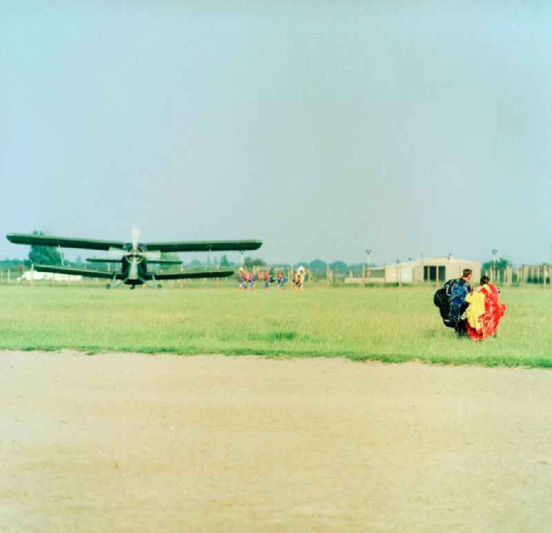 An aircraft of type Antonov AN-2 and paratroopers on the GST airfield in Leipzig-Mockau in Saxony in the area of the former GDR, German Democratic Republic