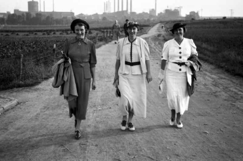 Three women go for a Sunday walk in Leuna in the federal state Saxony-Anhalt in Germany. In the background the Leuna works