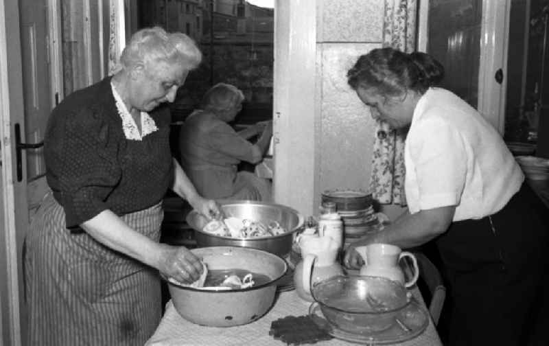 Two older ladies wash in enamel bowls dishes from in Leuna in the federal state Saxony-Anhalt in Germany