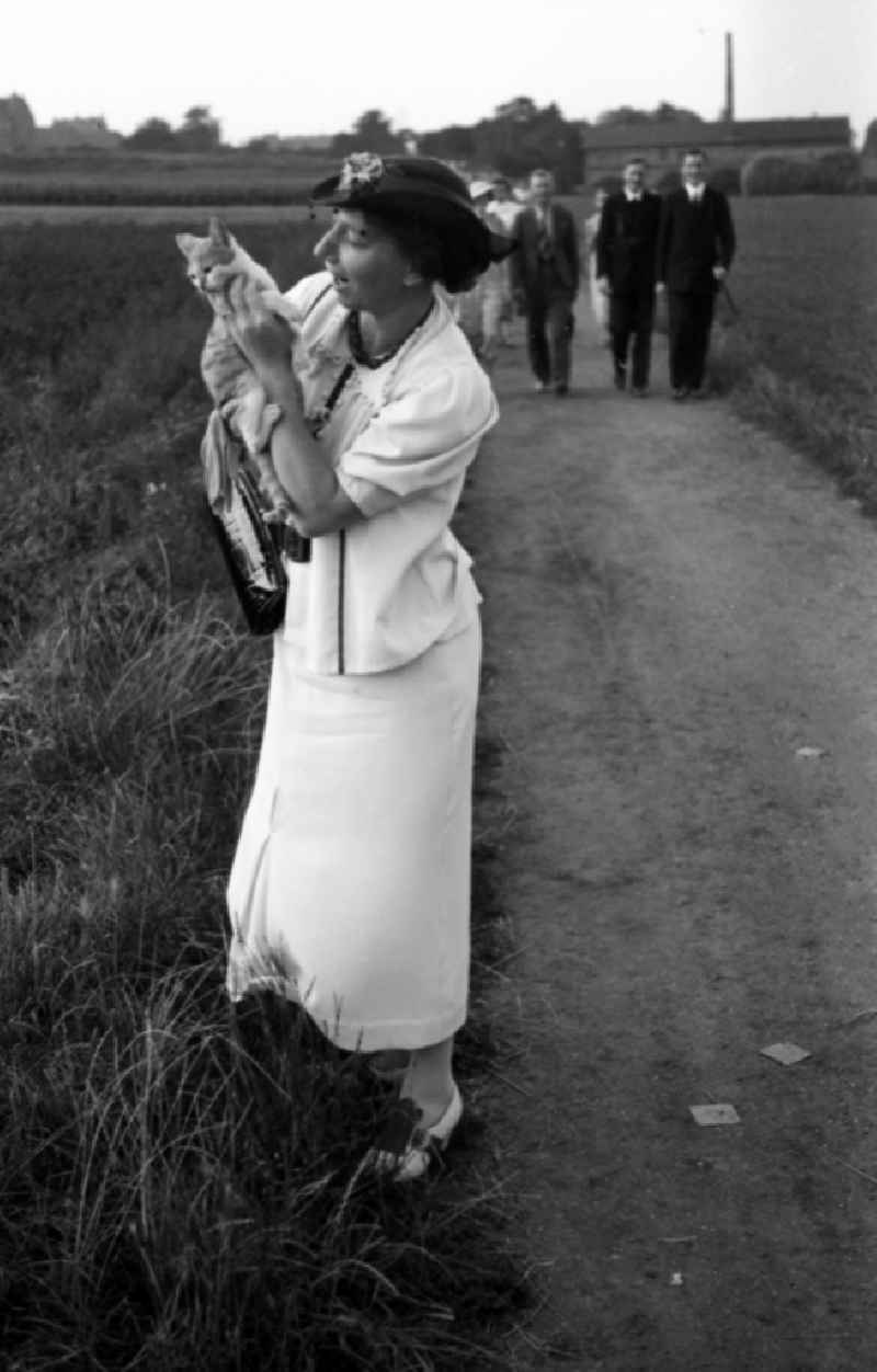 Sunday walk in Leuna in the federal state Saxony-Anhalt in Germany. In the background the Leuna works. A woman holds a cat on the arm