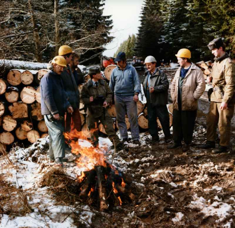 Border Patrol in snow in winter on the border strip in conversation with forestry workers in a wooded area near Lindewerra - Wahlshausen in present-day state of Saxony-Anhalt. The border guards of the border troops of the GDR - walls are equipped with AK-47 machine guns